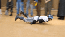 a person wearing a helmet and a referee 's uniform is laying on the floor