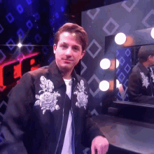 a man wearing a black jacket with white roses on it stands in front of a mirror