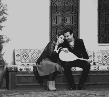 a black and white photo of a man playing a guitar and a woman sitting next to him