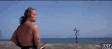 a shirtless man is holding a fishing rod in front of a fish with buzza written on the bottom