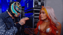 a man in a wrestling mask is pointing at a woman with red hair