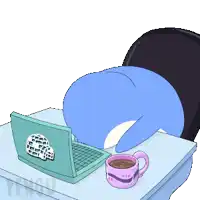 a blue penguin is laying on a desk with a laptop and a cup of coffee