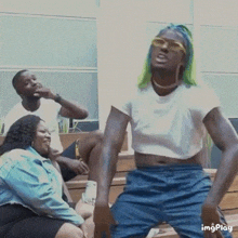 a woman with green hair is dancing in front of a group of people