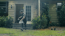 a man walking in front of a house with hbo max written on the bottom of the screen