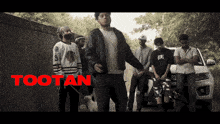 a group of men are standing in front of a car with the word tootan on the bottom right
