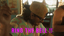a man wearing a hat and sunglasses says ring the bell !!