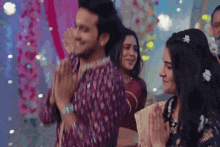 a man and a woman are standing next to each other with their hands together .