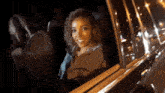 a woman is smiling while looking out of a car window at night
