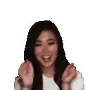 a woman with long black hair is smiling and waving her hands .