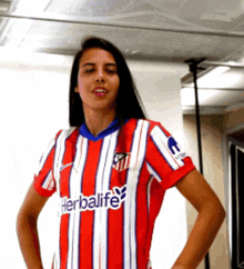a woman wearing a red and white striped shirt that says herbalife on the front