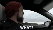 a man in a red hat is driving a car and the word what is above him