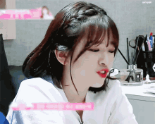 a girl with short hair and bangs is making a funny face while sitting at a table .
