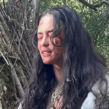 a woman with long dark hair has a bloody face