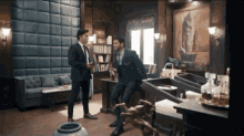two men in suits are standing in a living room talking
