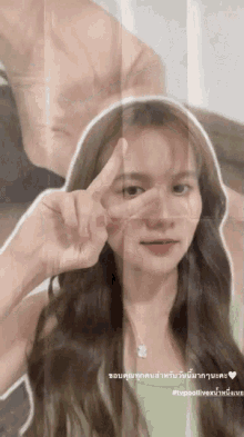 a woman in a green shirt is giving a peace sign with her fingers