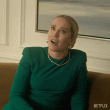a woman in a green dress is sitting on a couch with netflix written on the bottom right