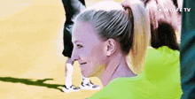 a woman with a ponytail is smiling and wearing a green shirt with wolfe tv written on it