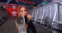 a woman is holding a wrestling belt in front of a sign that says night of champions