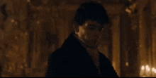 a man is standing in a dark room with candles in the background