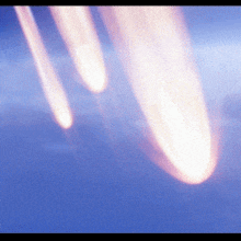 a blurred image of a blue sky with a few rockets flying through it