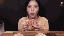 a young woman is eating a donut with a bite taken out of it .