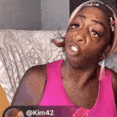 a woman in a pink tank top is sitting on a couch
