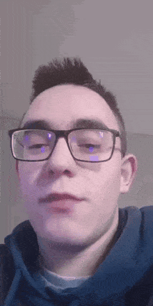 a young man wearing glasses and a blue sweatshirt