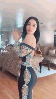 a woman in a dress is standing in a living room with a couch .