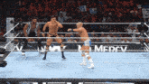 wrestlers in a wrestling ring with a mercy banner in the background