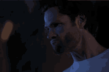 a close up of a man 's face with a beard in the dark