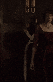 a woman in a red dress stands in a dark room