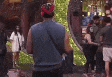 a man in a blue tank top is standing in front of a group of people .
