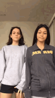 two girls are standing next to each other one wearing a sweatshirt that says ma asq