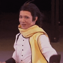 a man wearing a white shirt and a yellow scarf is dancing on a stage .