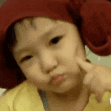 a baby wearing a red hat is making a funny face .