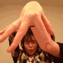 a woman wearing glasses and a plaid shirt is making a hand gesture