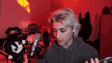 a young man stands in front of a rode microphone in a red room