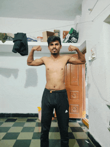a shirtless man flexes his muscles in a room with a door that says ' a ' on it