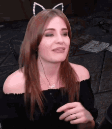 a woman wearing a cat ear headband is making a funny face while talking into a microphone