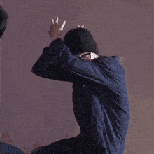 a man wearing glasses and a beanie is giving the middle finger