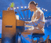 a man is playing a piano on stage and singing into a microphone