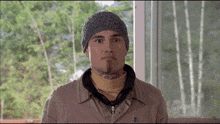 a man wearing a knitted hat and a jacket with the letter t on it