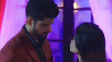 a man and a woman are kissing in front of a window in a dark room .