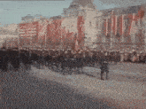 a group of people marching down a street in front of a building .