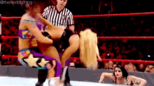 two women are wrestling in a wrestling ring with a referee watching .