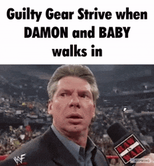 a man in a suit is talking into a microphone with the words guilty gear strive when damon and baby walks in below him