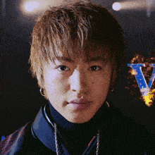 a close up of a young man 's face with the letter v behind him