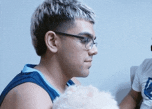 a man wearing glasses holds a white dog