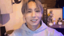 a young man wearing a purple hoodie is smiling in a room .