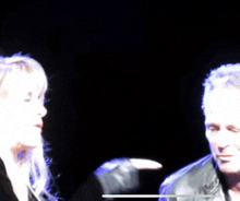 a woman singing into a microphone next to a man in a dark room